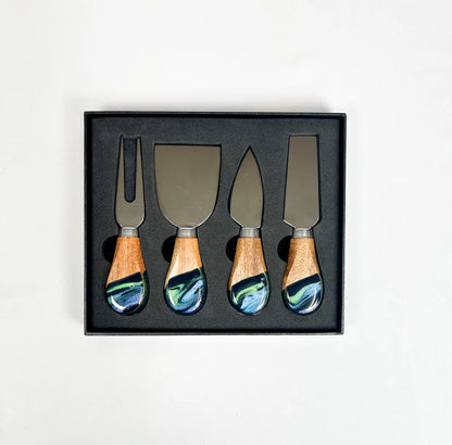 Set of four resin dipped cheese knives with wooden handles in a black box on a white background