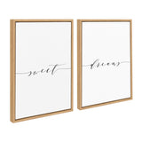 Two framed canvas art pieces with light wood frames, each featuring a single black word in elegant script: 'sweet' on the left and 'dreams' on the right, against a white background.