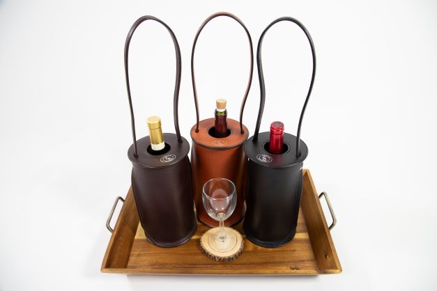 Enrico Bartolini Wine Totes in tan, dark brown, and black leather displayed on a table