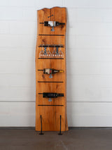 Vertical wine rack made from live edge Redwood with steel legs and shelves holding wine bottles and glasses.