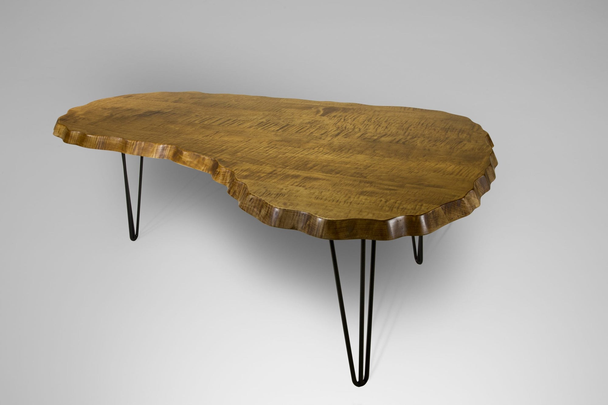 Wavy Tiger Maple Kidney Table with slender black hairpin legs set in a bright room