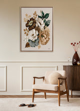 Neutral-toned framed canvas of large flowers in ivory, tan, and dark green, hanging above a mid-century modern armchair with beige upholstery and wooden frame.