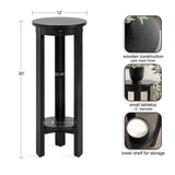 Tall black wooden side table with a 12-inch round top, lower circular shelf, and four vertical legs, featuring a satin black finish and storage space below