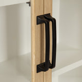 Close-up of black metal handles on light wood cabinet doors with white interior shelves, highlighting the contrast between handle and wood tones.