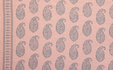 Pink fabric with repeating intricate blue paisley motifs and a vertical border stripe featuring smaller geometric patterns on the left side.