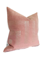 Square pillow cover in muted rose with an ivory geometric grid pattern woven into the textured fabric, displayed angled on a white background.