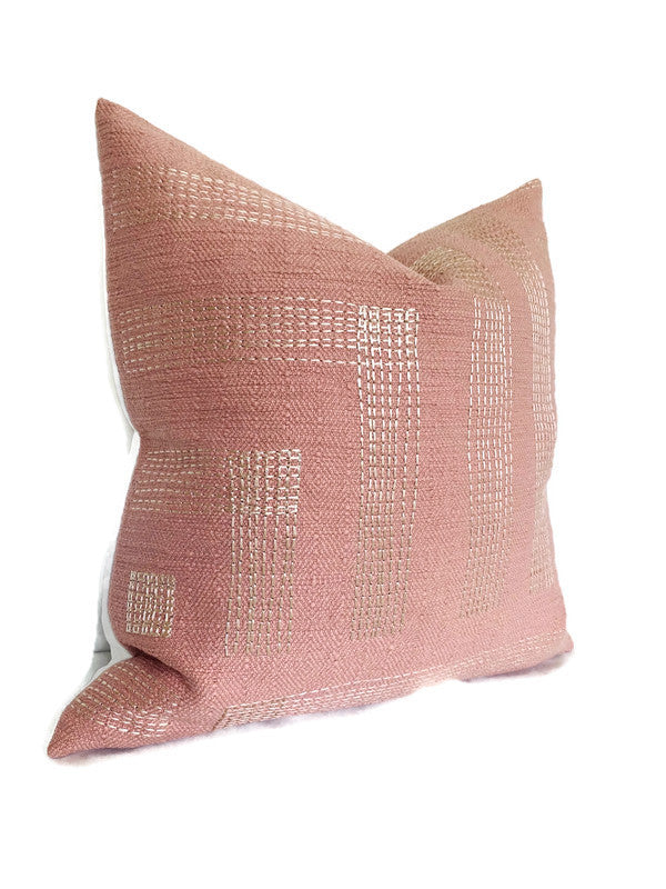 Square pillow cover in muted rose with an ivory geometric grid pattern woven into the textured fabric, displayed angled on a white background.