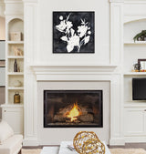 Black and white framed floral canvas featuring abstract white wildflowers on a black background, hanging centered above a modern gas fireplace in a white living room.