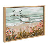 Framed canvas painting of a beach landscape with waves, flying birds, and foreground foliage in warm tones under a cloudy sky.