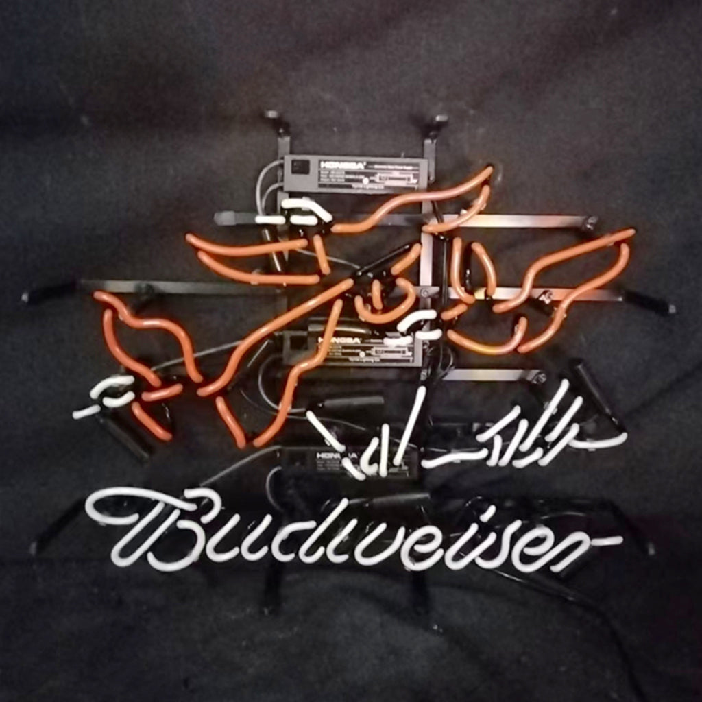 Orange and white neon lights shaped like flying pheasants above the white neon Budweiser script, set against a black background.