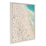 Aerial view of a crowded beach with numerous colorful umbrellas dotting the sandy shore next to turquoise ocean waves gently rolling in.