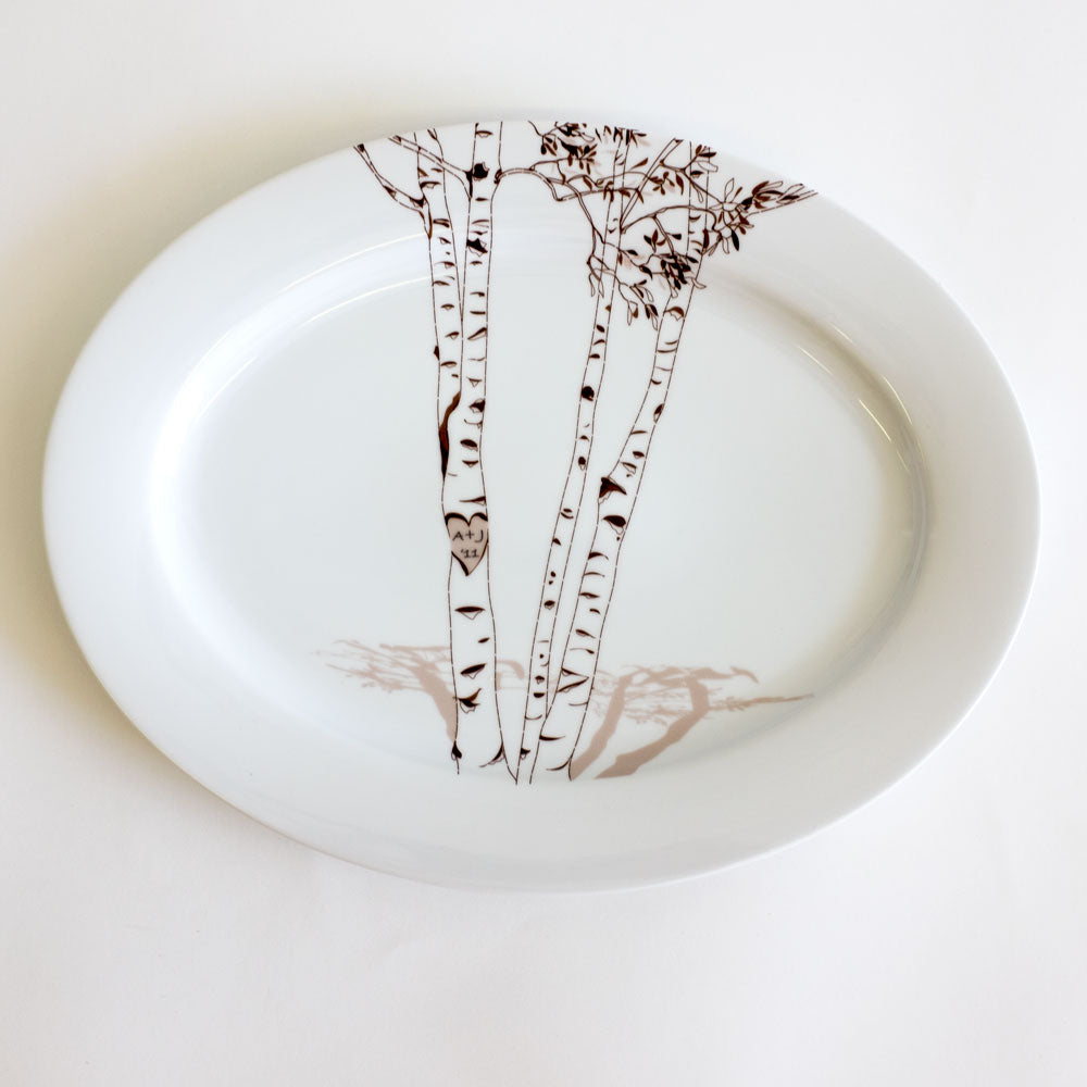 Oval white platter featuring a delicate black and brown birch tree illustration with carved heart and initials on the central trunk.