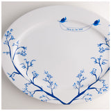 White oval ceramic platter decorated with blue branches and two blue birds holding a banner that reads 'Janie & Jim 2010' near the rim.