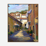 Sunlit narrow alley in a Mediterranean village with beige buildings, laundry hanging on lines, terracotta pots, and distant roofs under a blue sky with soft clouds.
