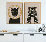 Two framed canvas art pieces on a white wall feature minimalist animal portraits: a lion with golden mane shapes on beige linen and a black and white striped tiger with yellow eyes.