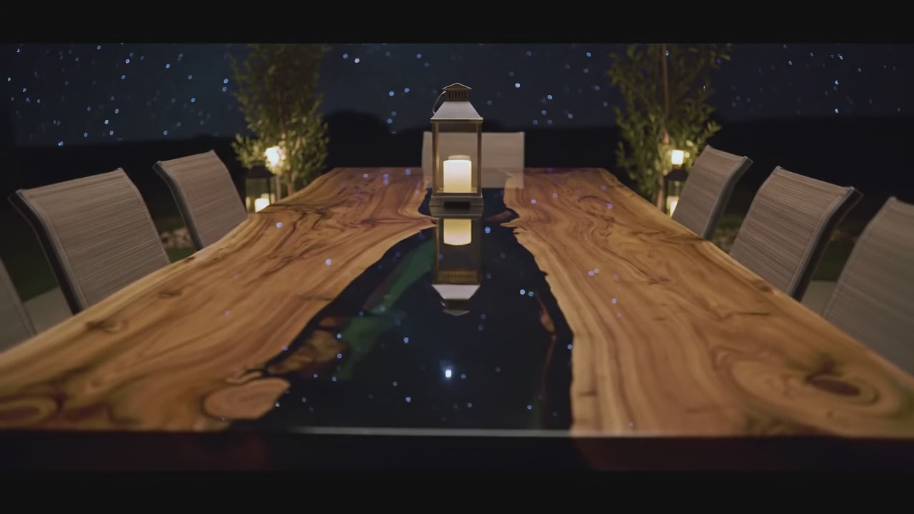 Load video: A luxury walnut wood dining table with deep epoxy resin river detail. The camera slowly pans across the tabletop, highlighting the smooth resin finish, natural grain patterns, and handcrafted design. Light reflections dance on the surface, showcasing the elegance and craftsmanship of the custom dining table