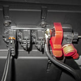 Close-up of a black electrical component with three plug connectors, two red safety lock clips, and attached black cables secured by screws.