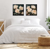 Bedroom with white bedding under two square framed paintings of creamy white floral bouquets on dark backgrounds, flanked by woven natural fiber furniture and a plant near a sheer curtain.