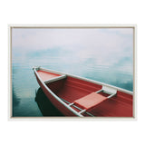 Red rowboat with a red seat cushion floating calmly on still, light blue water with gentle ripples in a framed canvas print.