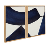 Two framed canvas artworks with bold abstract navy blue shapes on white backgrounds, set in light wood frames and displayed side by side with a slight angle.