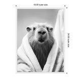 Black and white close-up of a capybara wrapped in a soft towel, looking directly at the camera with its snout prominent and ears slightly back.