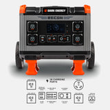 Front view of a dark gray and orange portable power station with four 120V AC outlets, multiple USB ports, an LED display reading 42, and two large rear wheels for mobility.
