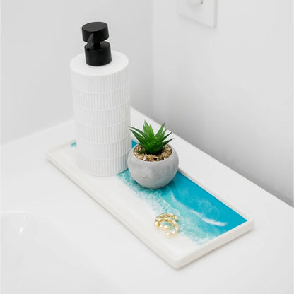 White resin ceramic tray, small potted plant, and ring on a decorative tray with blue resin design.