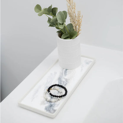Jewelry set on a white resin ceramic tray with a small plant in the background