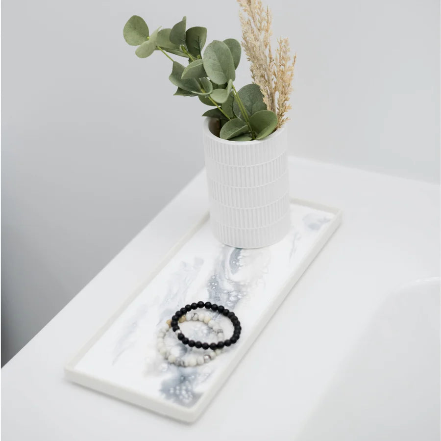 Jewelry set on a white resin ceramic tray with a small plant in the background