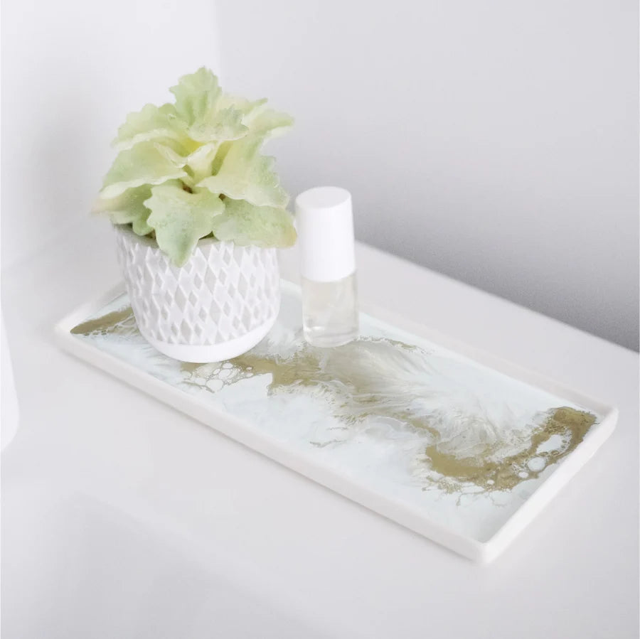 Decorative resin ceramic tray with a small plant and bottle on a white surface