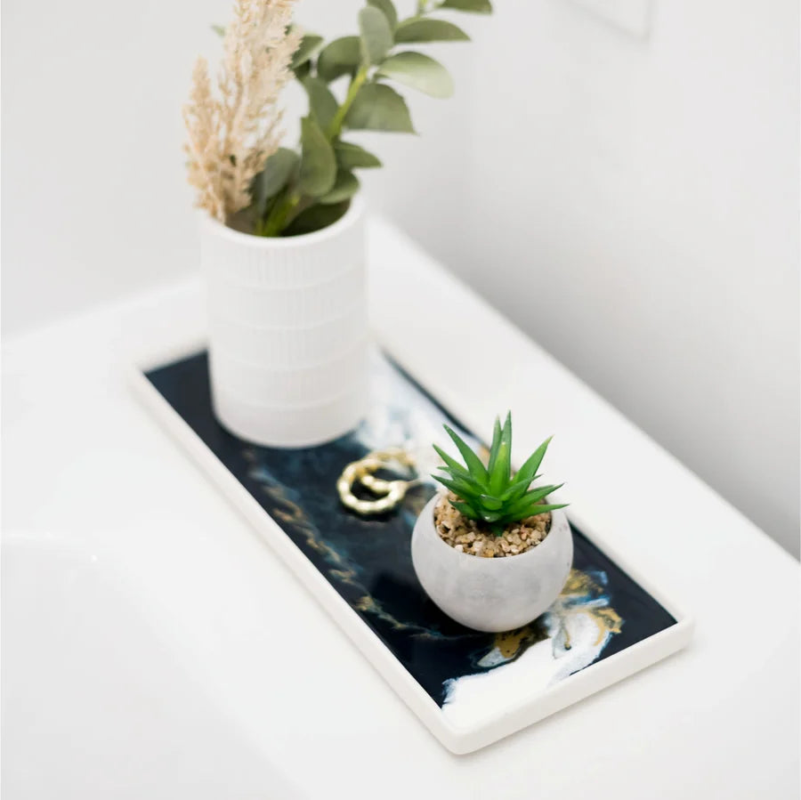 Small green succulent in a white pot on a decorative resin ceramic tray with abstract design