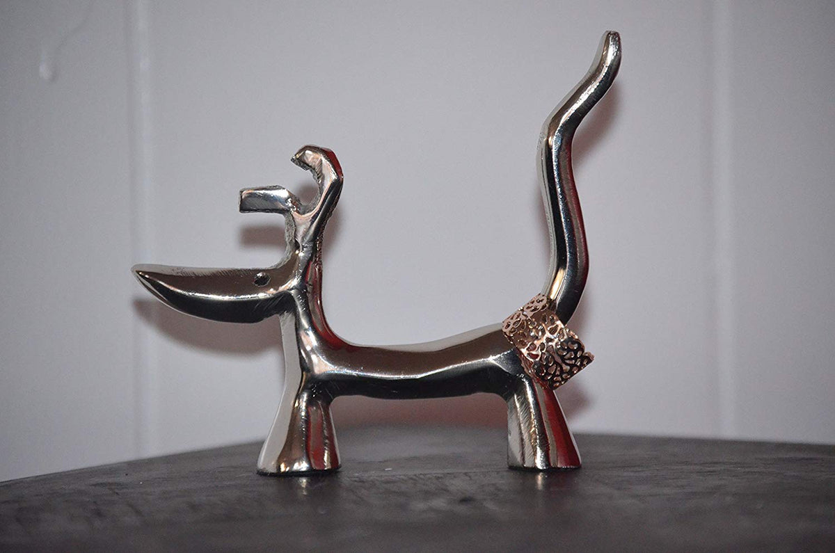 Silver-finished dog-shaped ring holder with a long curved tail holding a textured ring, standing on four short legs against a plain background.