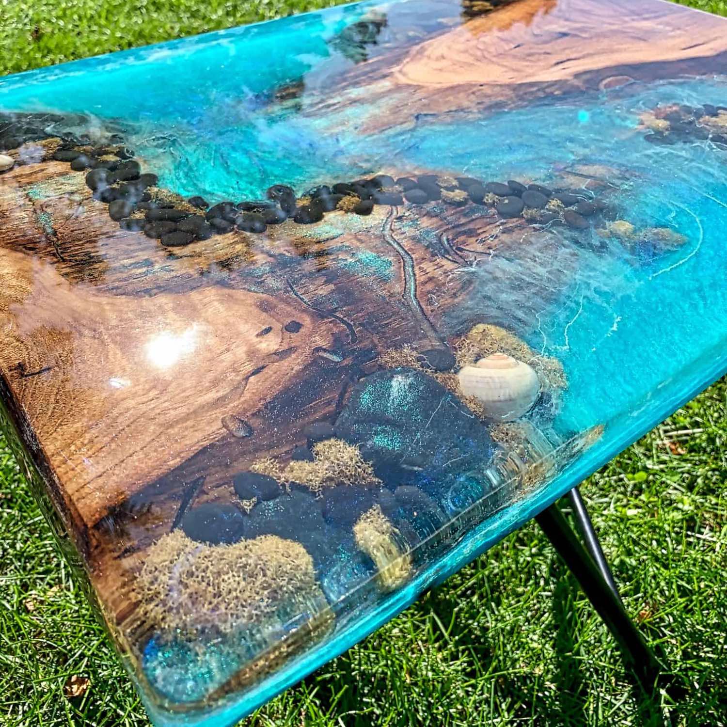 Table with a natural wood top and blue resin finish on grass