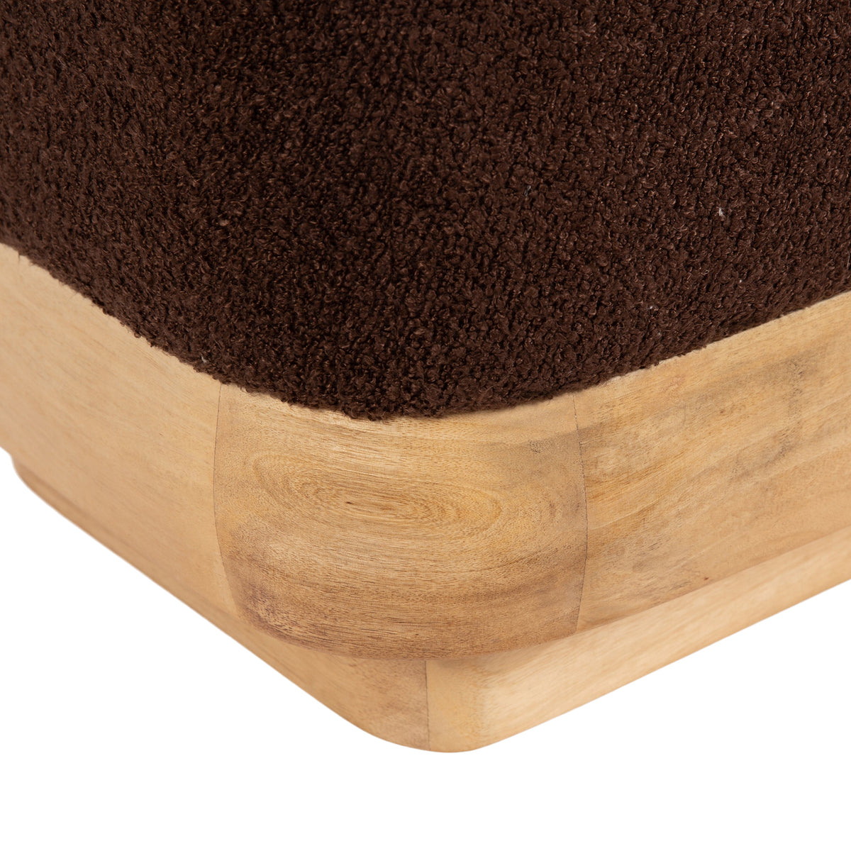 Corner of a square ottoman with dark brown textured fabric upholstery over rounded light wood base with visible wood grain and joined panels.