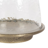 Close-up of a glass candle holder with a textured, hammered clear glass dome and a speckled gold metal base ring.