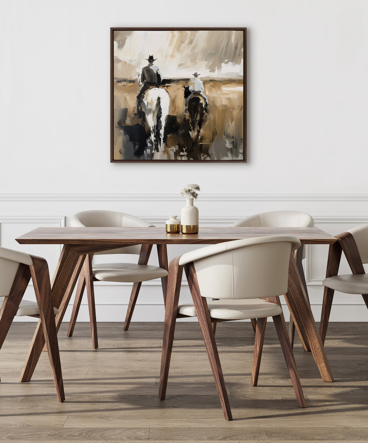 Neutral-toned abstract painting of two cowboys on horseback from behind, with loose brushstrokes in beige, brown, and black, framed and hung above a modern wood dining table with cream chairs.