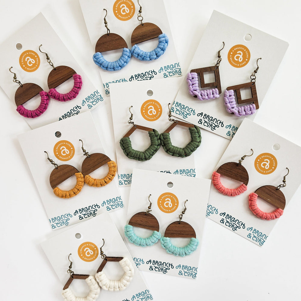 Colorful macrame knotted earrings in circle shape hanging against a neutral background