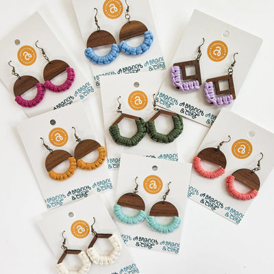 Colorful macrame knotted earrings in circle shape hanging against a neutral background