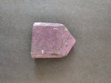 Polished purpurite lapidary stone with deep purple color and subtle brown inclusions, shaped with an angled point on one end, against a gray background.
