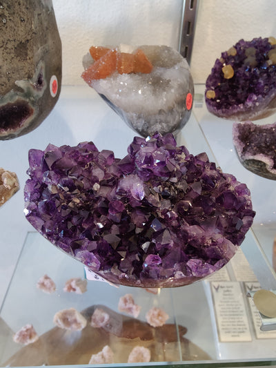 Amethyst geode sculpture with a flower-shaped crystal formation, polished edges, resting on a white background