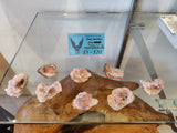 Small pink amethyst clusters displayed on a wooden slab under glass, with a blue price sign indicating $5 to $20 each.