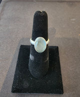 Oval aquamarine cabochon set in a polished sterling silver ring displayed on a black velvet ring holder.