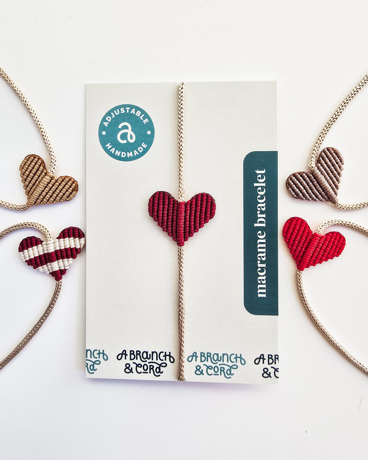Five macrame bracelets with heart-shaped patterns in shades of red, beige, and brown, one displayed on a card labeled ‘macrame bracelet’ and ‘adjustable handmade’.