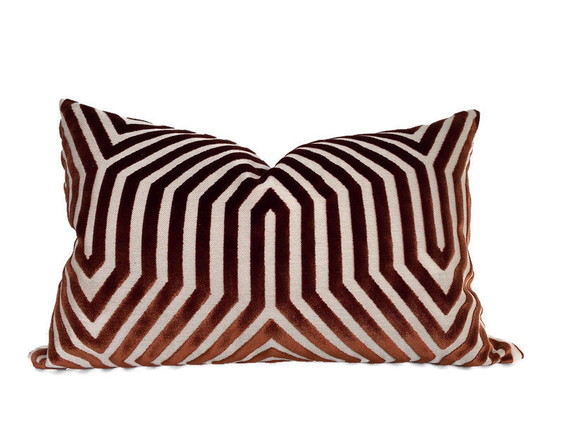 Rectangular pillow with a bold geometric pattern in rust and dark brown velvet, featuring concentric angular lines forming a symmetrical design.