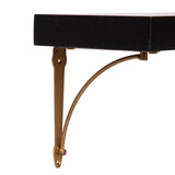 Close-up of a black rectangular wooden shelf with a curved, antique brass-colored metal wall bracket supporting it from underneath.
