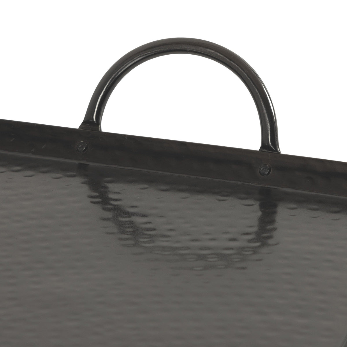 Close-up of a black hammered metal tray edge with a rounded handle casting a reflection on the textured surface below it.