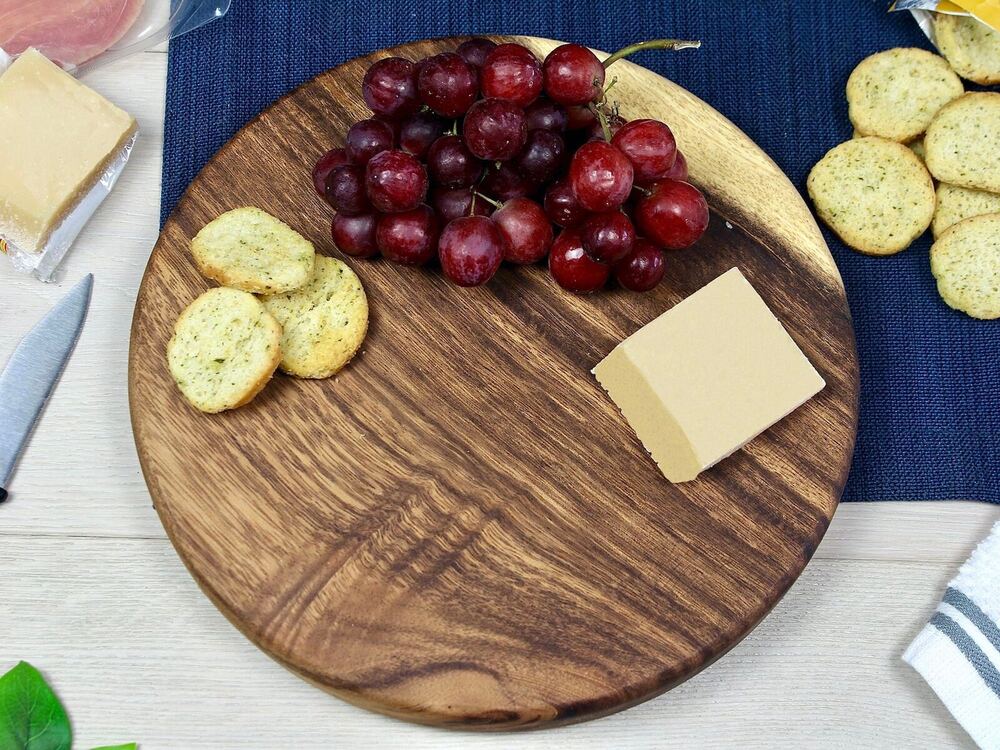 Small round charcuterie board made of East Indian Walnut with finger relief on backside