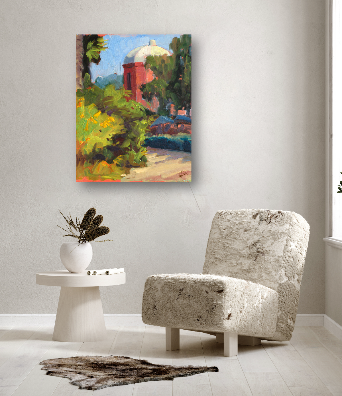 Impressionist painting of a red tower with a white dome surrounded by green foliage, displayed on a light wall above a textured cream chair and round white side table.
