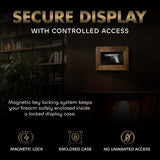 Wood-framed wall-mounted display case showing a pistol inside, set against a dark wall with a bookshelf and plants in dim lighting.