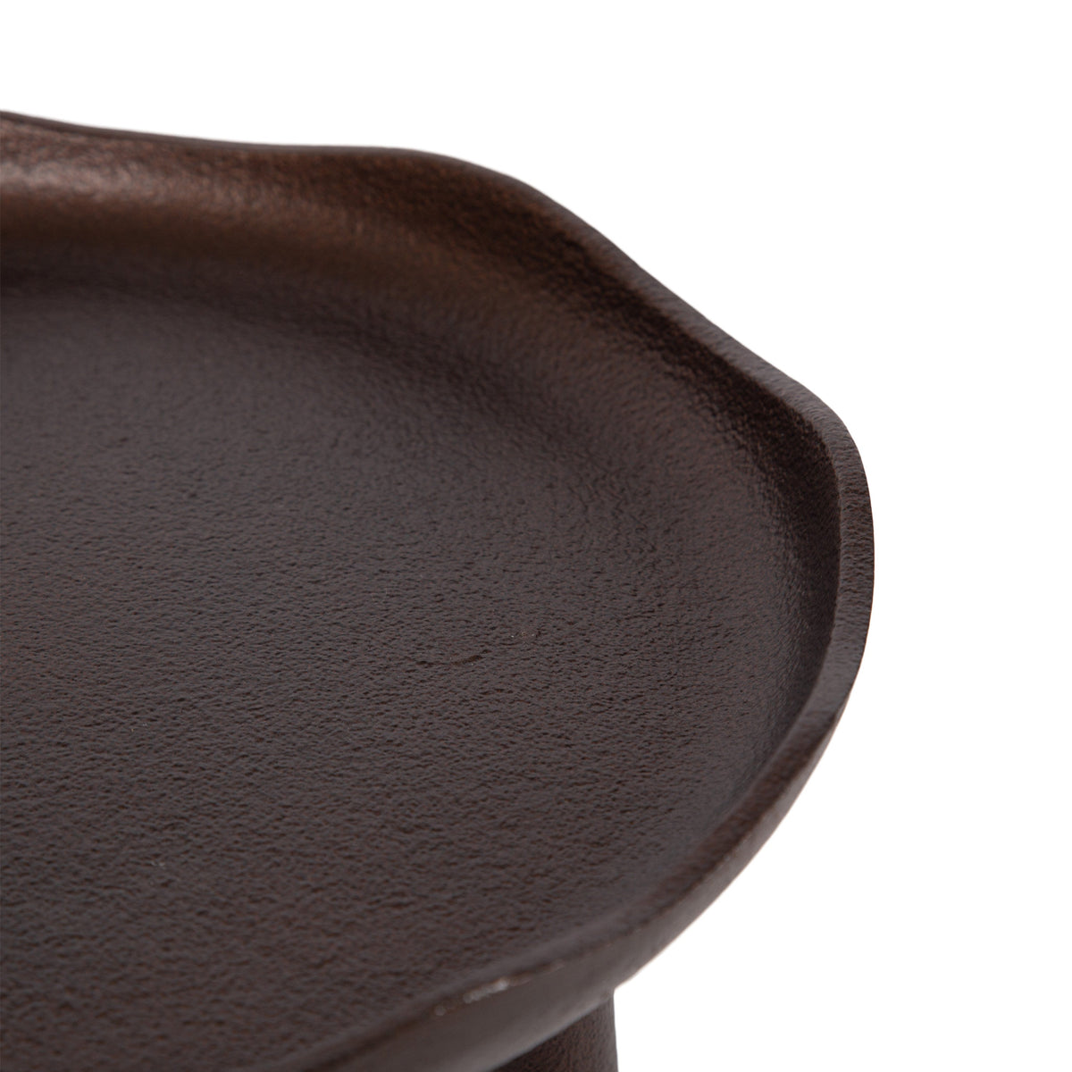 Close-up of a dark brown, round, slightly irregular textured tray with a raised edge and a subtle lip detail on one side, on a white background.